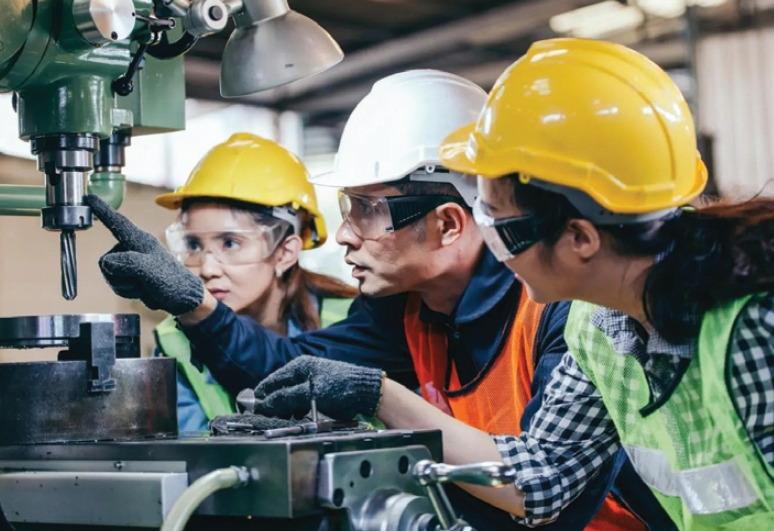 안전모와 보호안경을 착용한 학생들이 여름방학 인턴십 프로그램을 통해 현장 실무 경험을 쌓기 위해 기계 작동을 배우고 있다. [로이터]