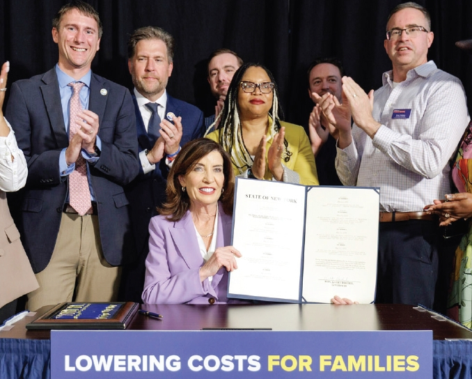 캐시 호컬 뉴욕주지사(가운데)가 28일 올바니에서 전날 밤 주의회를 통과한 2026~2027회계연도 예산안에 서명한 뒤 들어보이고 있다.  [사진 뉴욕주지사실]