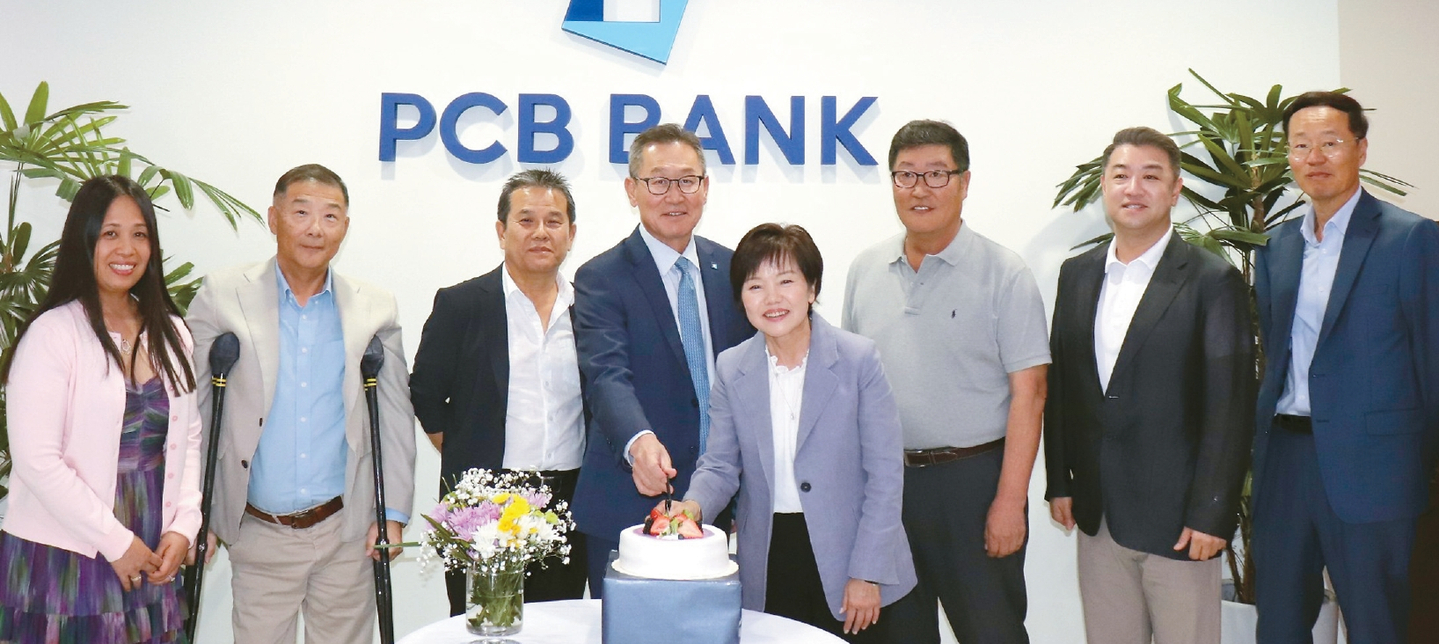 PCB뱅크(행장 헨리 김) 롤랜드하이츠 지점(18160 Colima Rd.)이 지난 3일 오픈 20주년을 맞아 지점을 방문한 고객들에게 다과와 사은품을 증정했다. 김 행장(왼쪽에서 4번째)과 카니 김 롤랜드하이츠 지점장(왼쪽에서 5번째) 등 직원들이 축하 케이크를 함께 자르고 있다.                        [PCB뱅크 제공]  